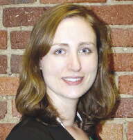 A portrait photo of a woman standing in front of a brick wall