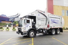 A garbage truck sits in a parking lot