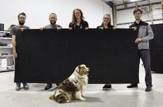 Five members of the Multiscale Systems team holding materials, pictured with the facility's dog.