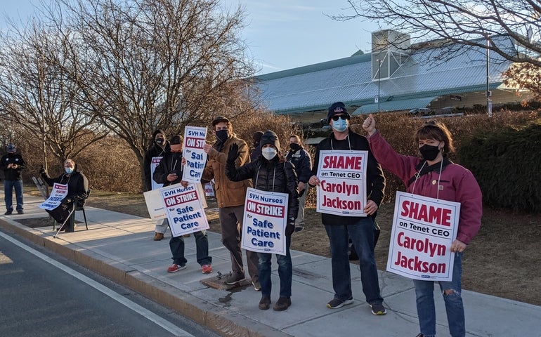 A group of striking workers hold picket signs outside