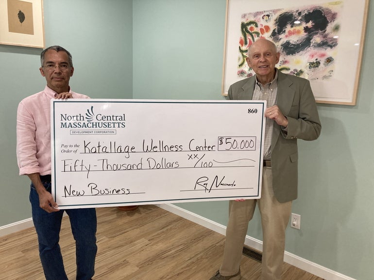 Two men stand with a giant check