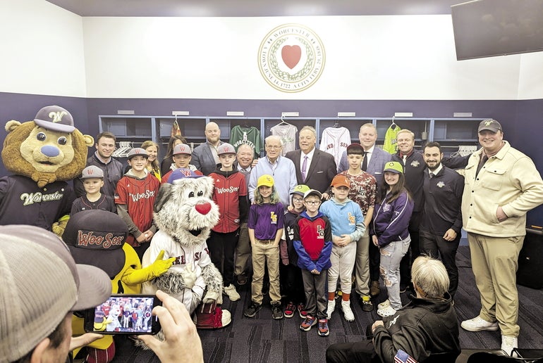 A group of children, sports mascots, and executives gather for a group photo.