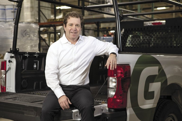 Greenwood Industries owner David Klein sits on the back of one of his company's trucks. 