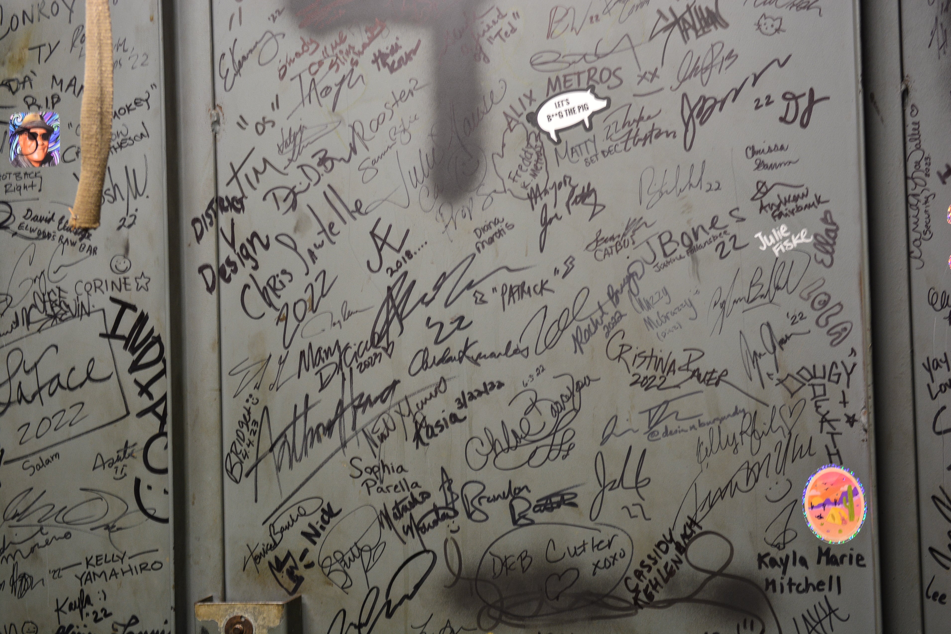 A large amount of signatures on the door of a freight elevator.