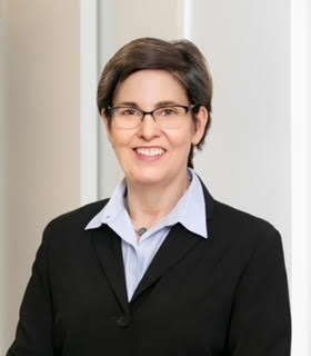 A woman with glasses in a suit