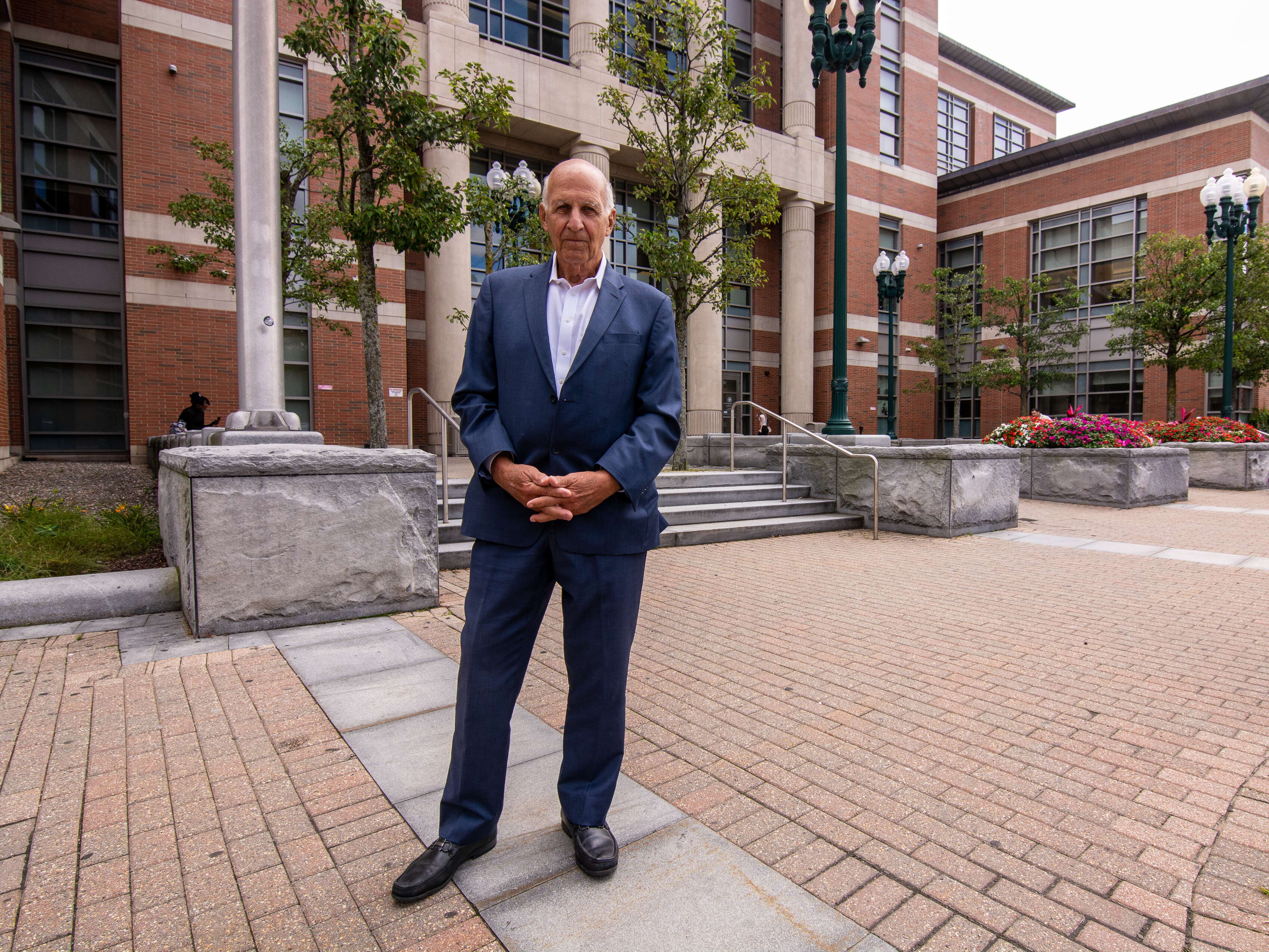 A man in a suit stands in front of a court house