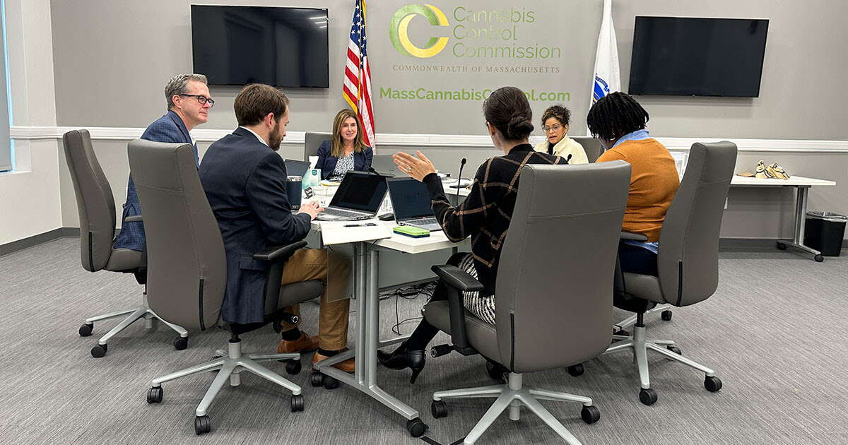 Six people sit around a table at a meeting 