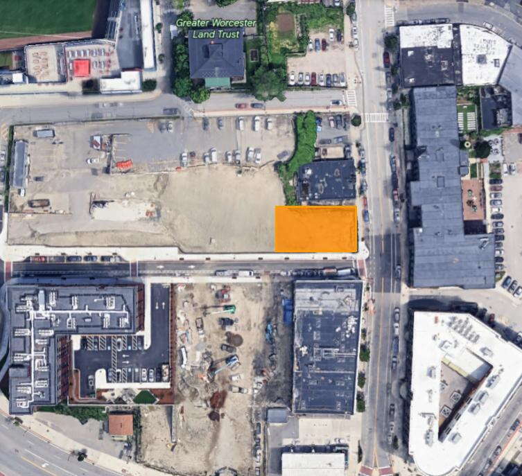 A satellite image showing an urban area with an open lot, part of the open lot is highlight orange