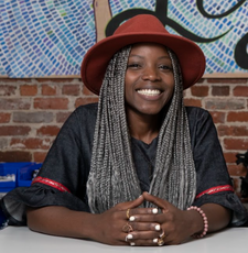 A woman smiles at the camera while wearing a red hat and black top.