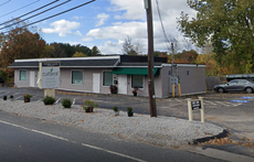 A small one-story building with a parking lot in front