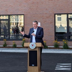 A man at a podium in front of an apartment building