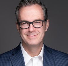 Man with glasses in suit smiles