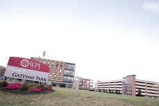 A college campus sits behind a green lawn with a sign reading "WPI Welcome to Gateway Park"