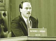 A black and white photo of a man in a suit leaning on a podium