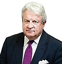 A headshot of a man with white hair wearing a black suit jacket, white button down, and blue tie