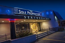 Steps lead up to a restaurant building with a sign reading "The Sole Proprietor" above a large awning