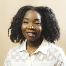 A woman with a white button down blouse smiles for the camera.