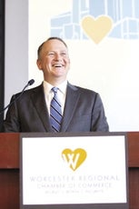 A man wearing a suit and tie stands behind a podium.