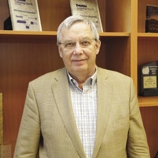 A man in a beige suit and glasses