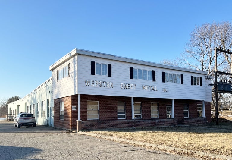 A photo of a red brick a white sided industrial building with metallic lettering reading "Webster Sheet Metal Inc."