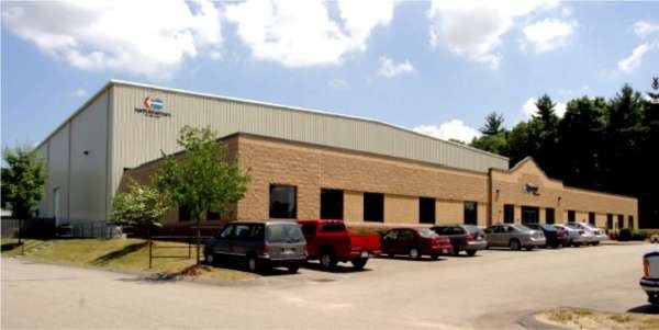 A large industrial building with a parking lot in front