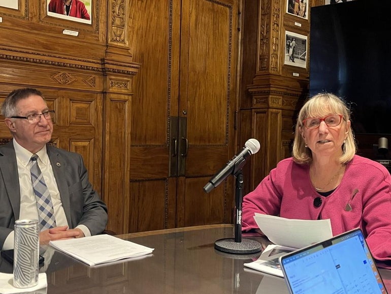 A man and a woman sit at a table with a microphone on it