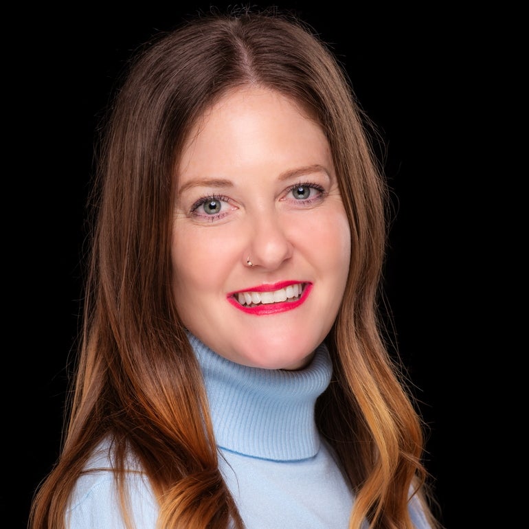 A woman in a blue turtleneck with a black background