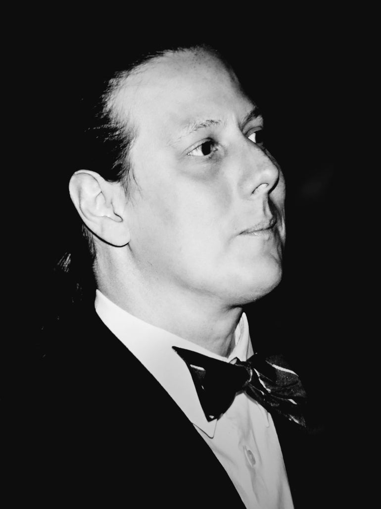 A black-and-white photo of a man in a tux looking to the upper right