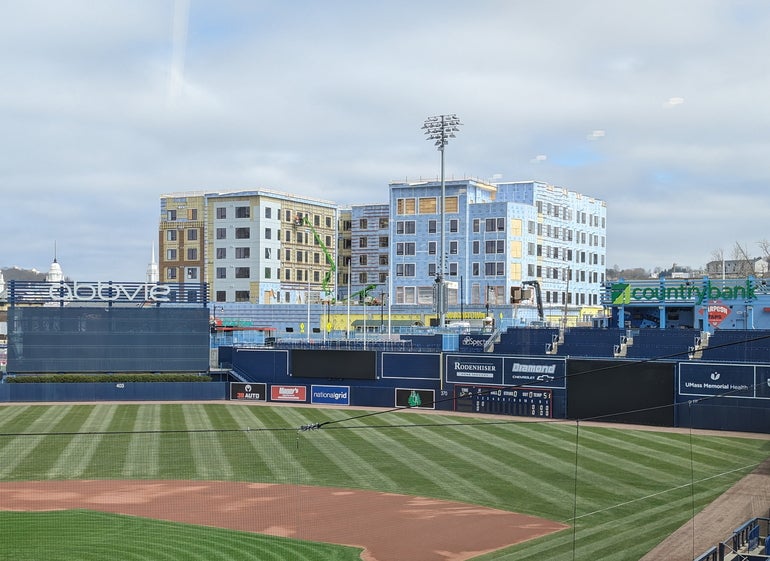 An apartment building being constructed beyond the walls of a baseball stadium