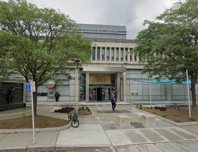 A building with with a large entryway with trees on either side. 