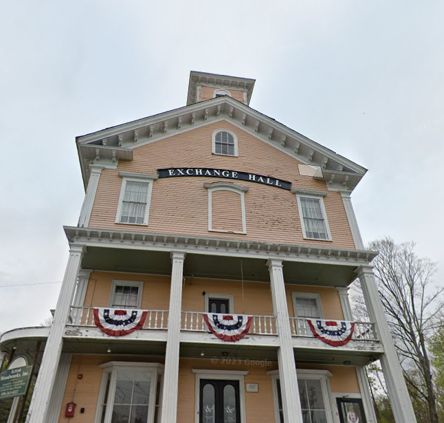 A four story wooden building with columns and a porch