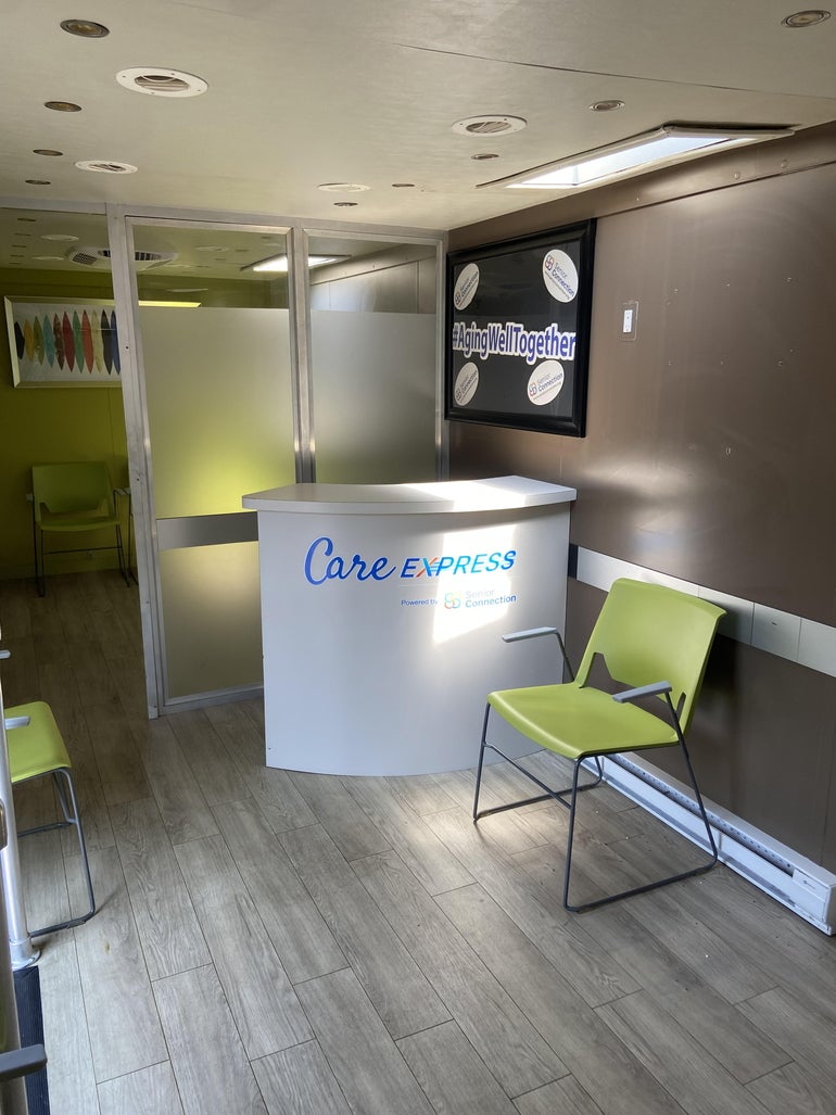 A small waiting area with green chairs within a mobile service van.