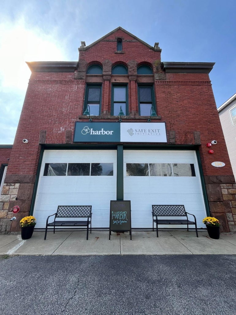 A brick building with two white garage doors and three windows