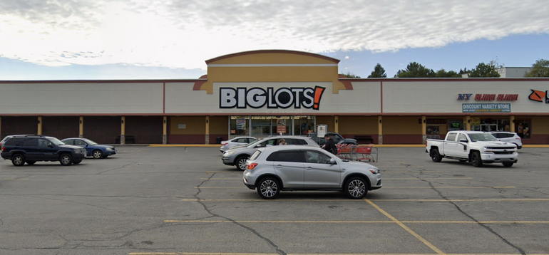 A strip mall with a large "Big Lots" sign sits behind a parking lot with cars.