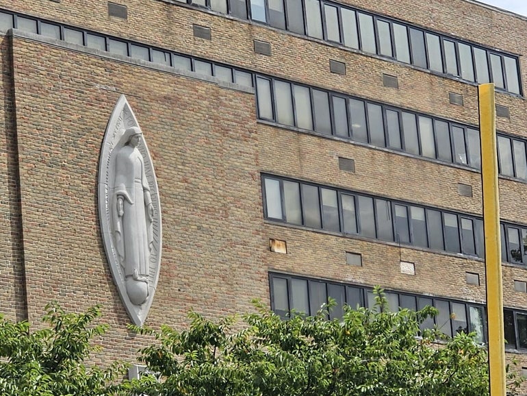 Outside a brick building with a grey statue attached to it