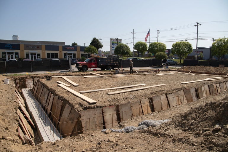 A foundation being constructed in a shopping plaza with workers in the background