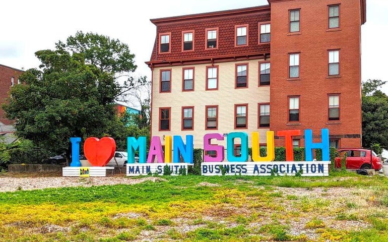 A sign reading "I <3 MAIN SOUTH" sits behind a plot of grass and gravel.