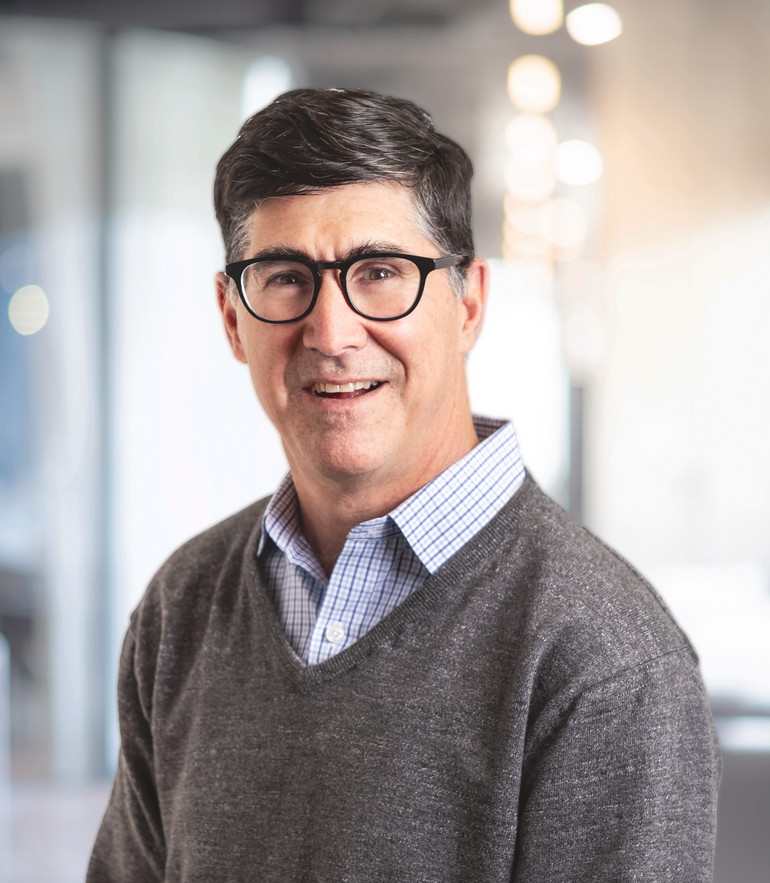 A man in glasses and a sweater smiles