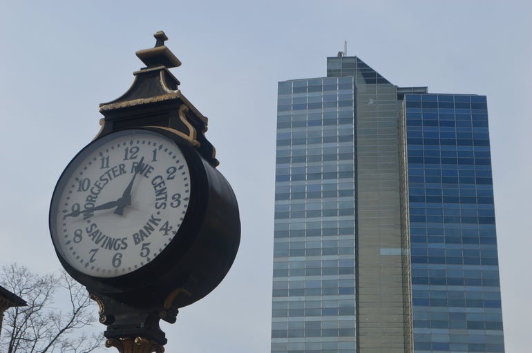 Blue skyscraper sits behind large street clock