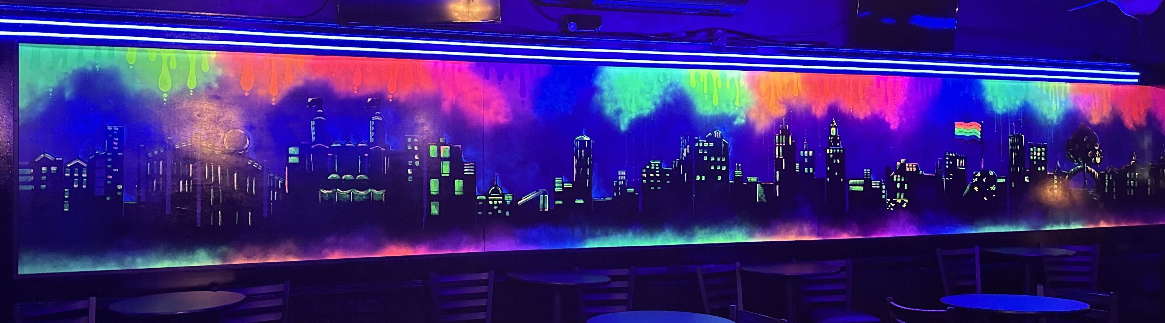 A mural depicting the Worcester cityscape at night with green, red, pink, and orange paint.
