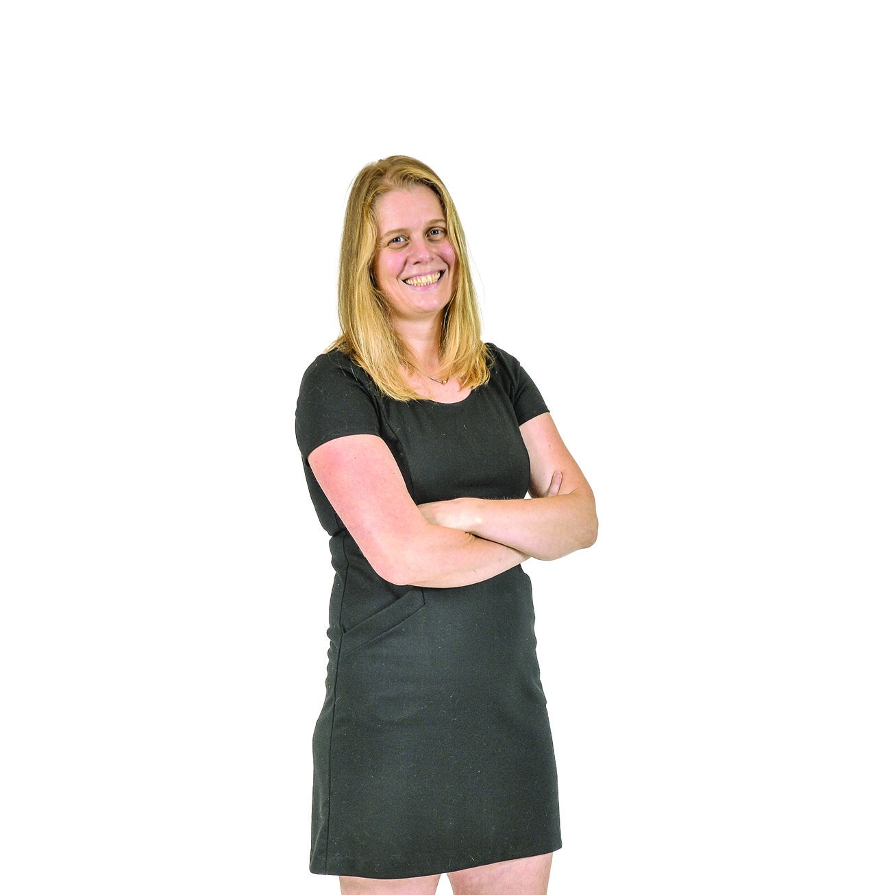 A woman in a black dress smiles with arms folded