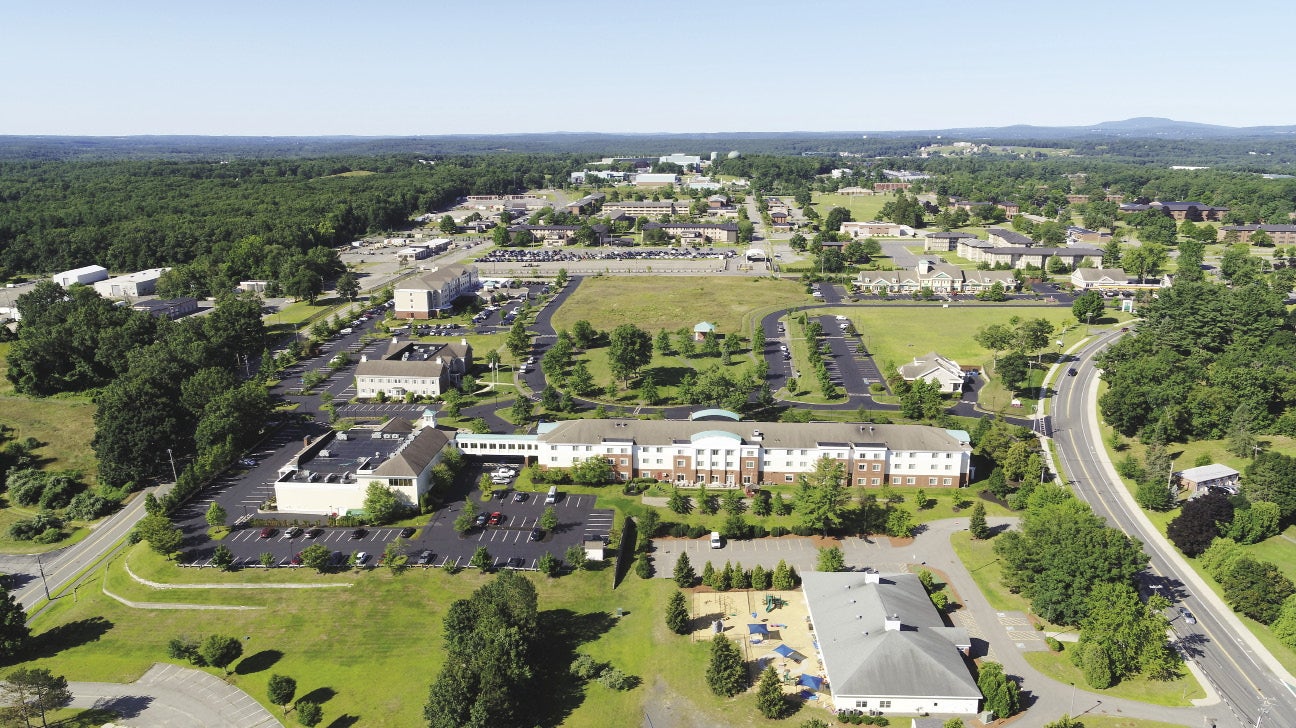 An aerial view of buildings amidst green lawns, greets, and streets 