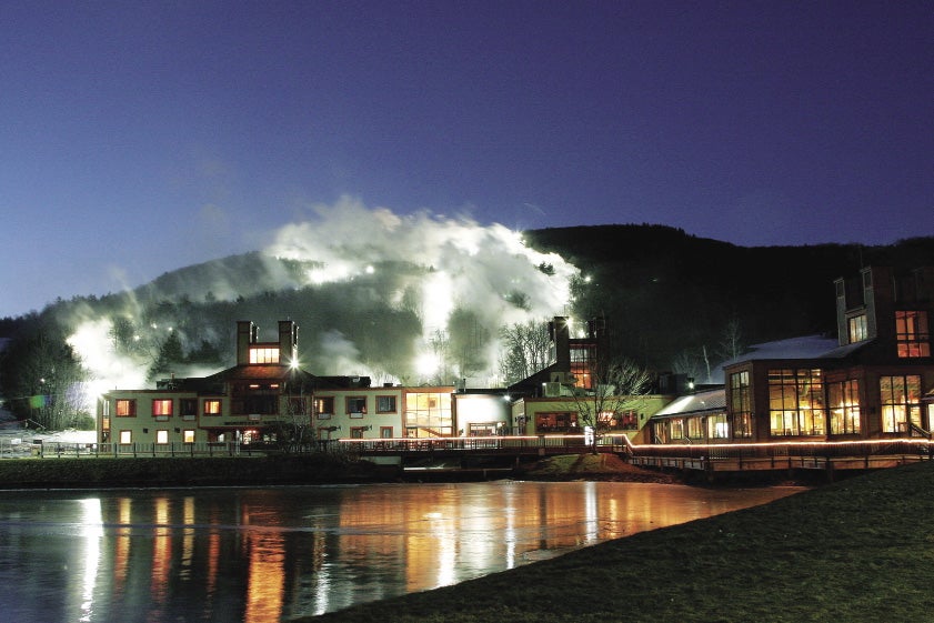 A ski resort behind a pond at night in front of mountains