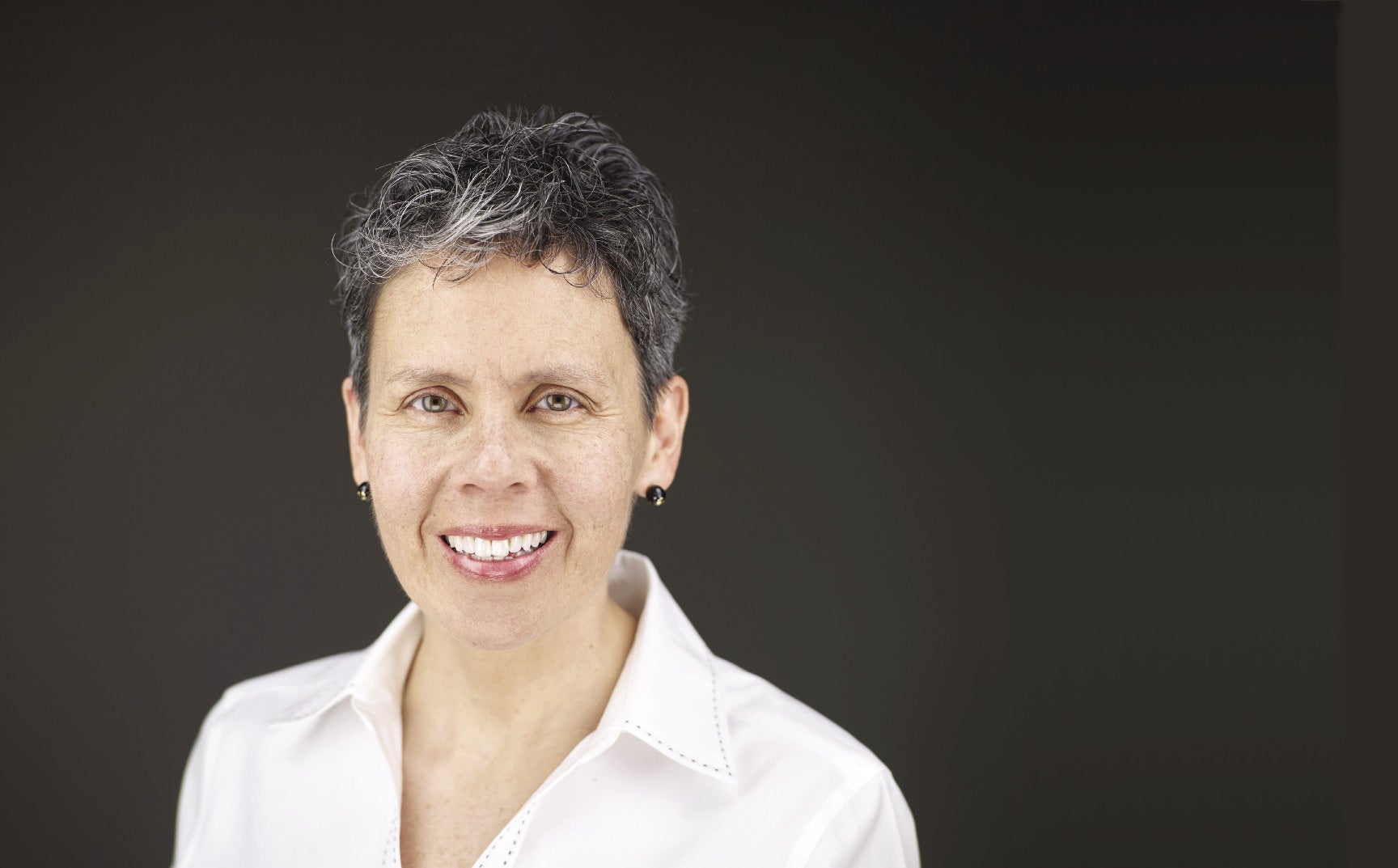 A woman with grey and white hair wears a white button down.