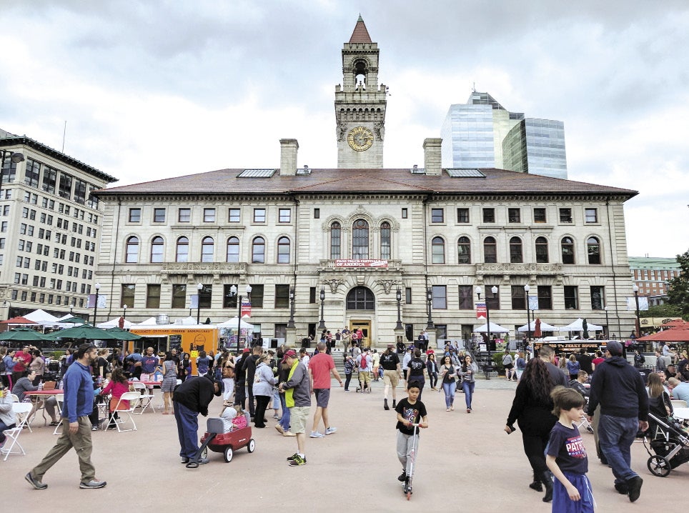 Crowds of people gather and walk around the front entrance to Worcester's City Hall.