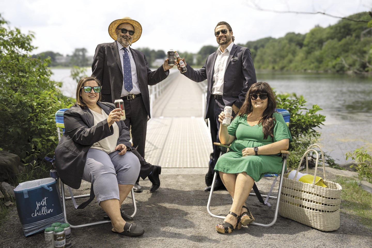 Two men and two women enjoy sit and stand on the shores of a lake bisected by a floating boardwalk.