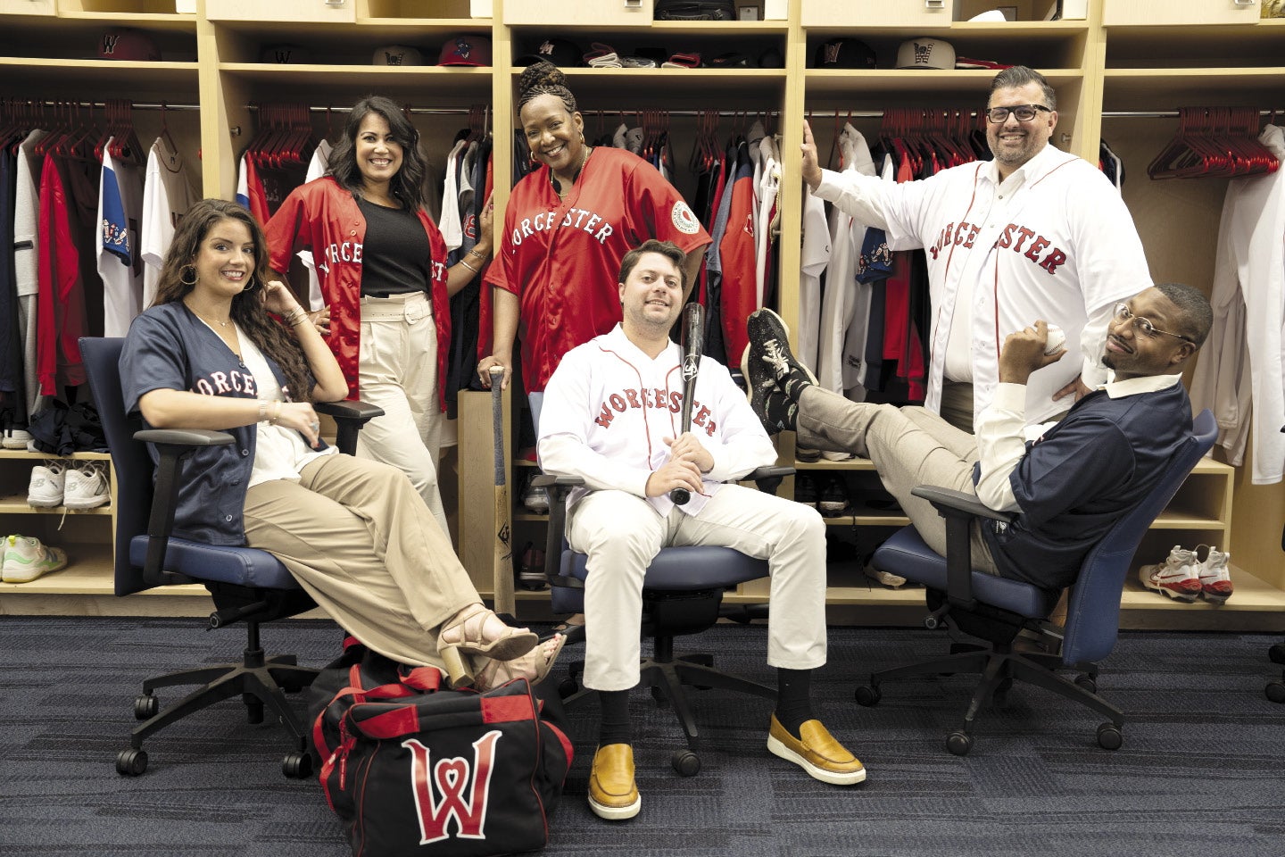 Three women and three men sit in the Worcester Red Sox clubhouse.