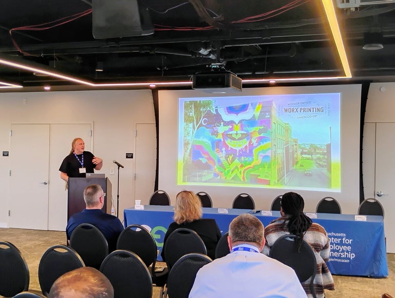Man stands at podium giving PowerPoint presentation to audience