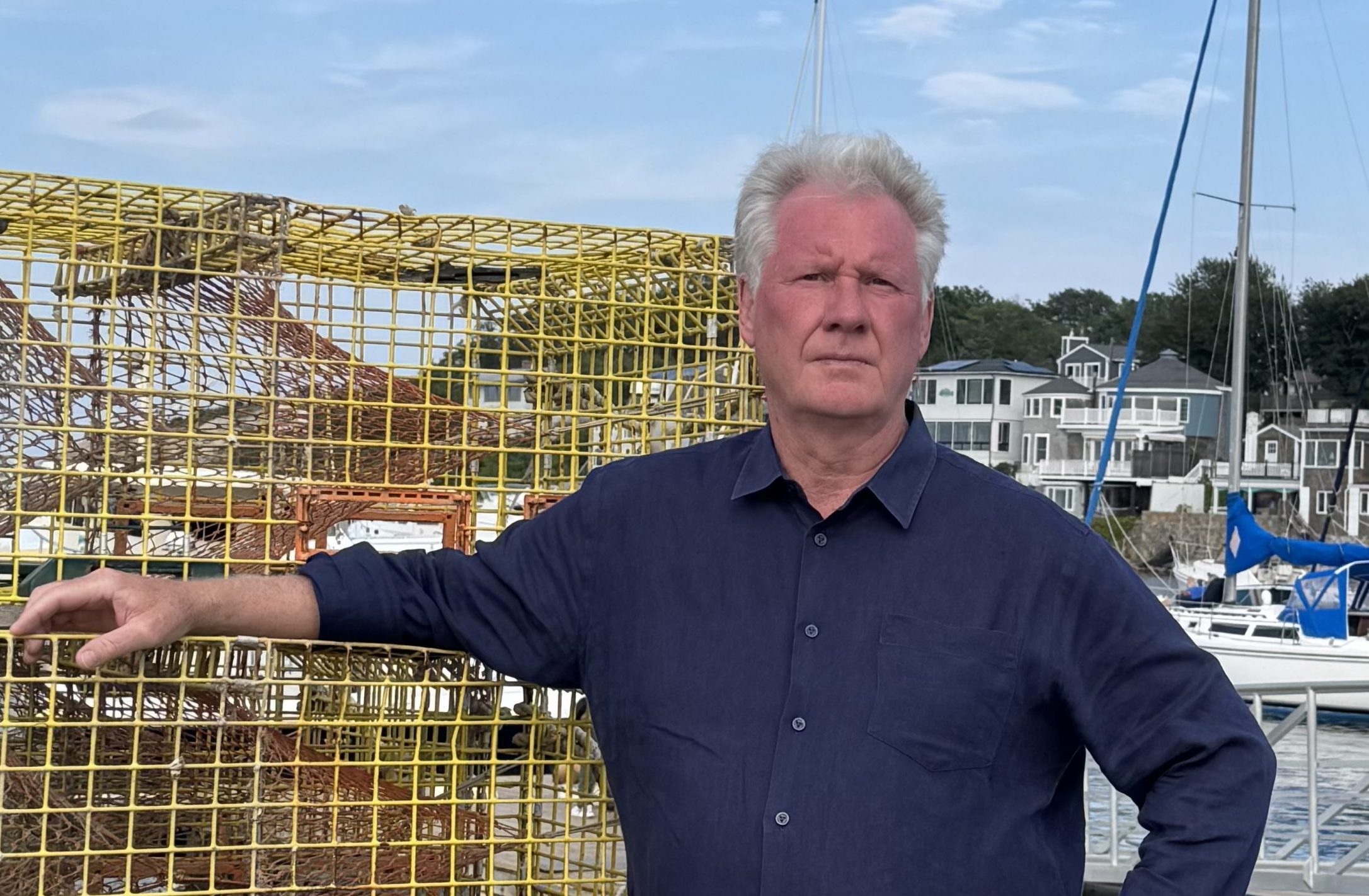2025 Photo of JK Jr. with lobster traps 1 (8.20) A man leans against lobster traps
